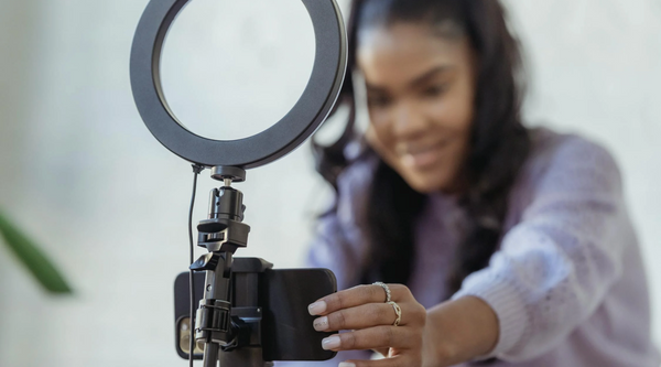 A social media influencer with a selfie light positioning her phone, ready to record a video