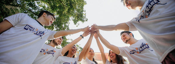 A group of young people wearing matching t-shirts in a team huddle.