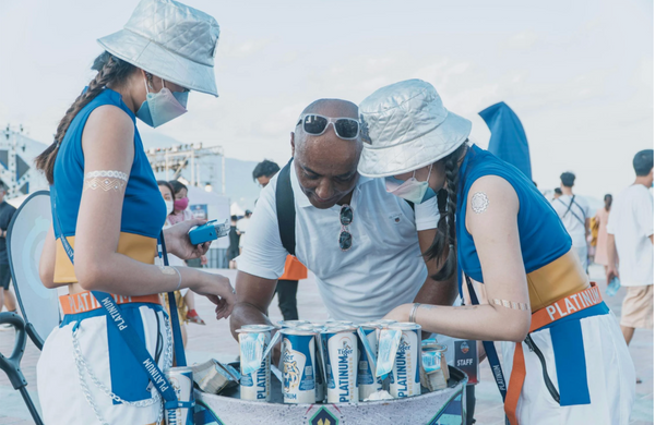 Two workers wearing promo merchandise at an event while a customer signs something