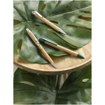Borneo bamboo ballpoint pen in green laying on top of a leaf with other pens.