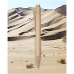Terra corn plastic ballpoint pen in sand in front of a desert